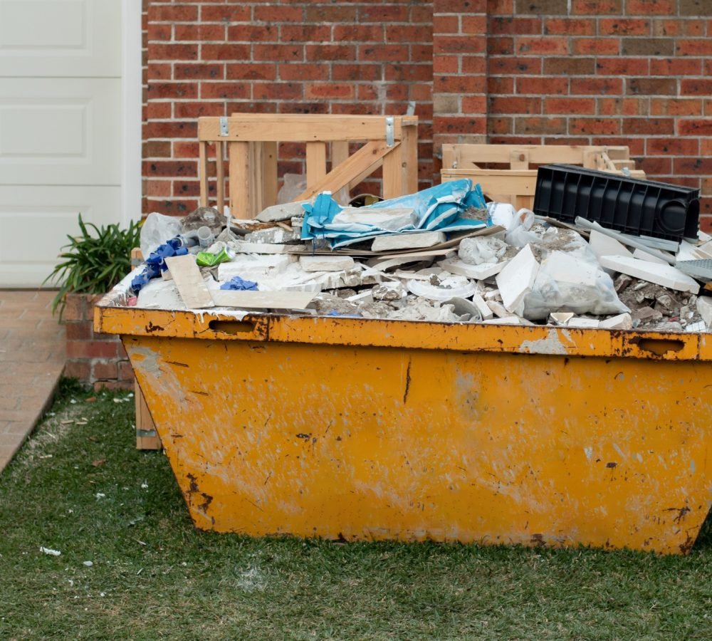 Skip bin full of household waste rubbish. House clean up and renovation concept. Waste management